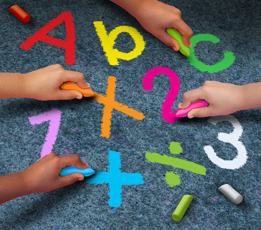 42215286 - education community learning concept as a group of children holding chalk writing and drawing reading and math symbols on pavement as a metaphor for working together in friendship for school support.