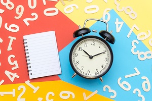 notebooks and alarm clocks in the center of colorful paper and scattered numbers