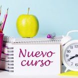 On a light table there are books, stationery, a white alarm clock, an apple. Next to it is a notebook with the text BACK TO SCHOOL. Educational concept.