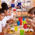 Primary school kids eating at a table in school cafeteria