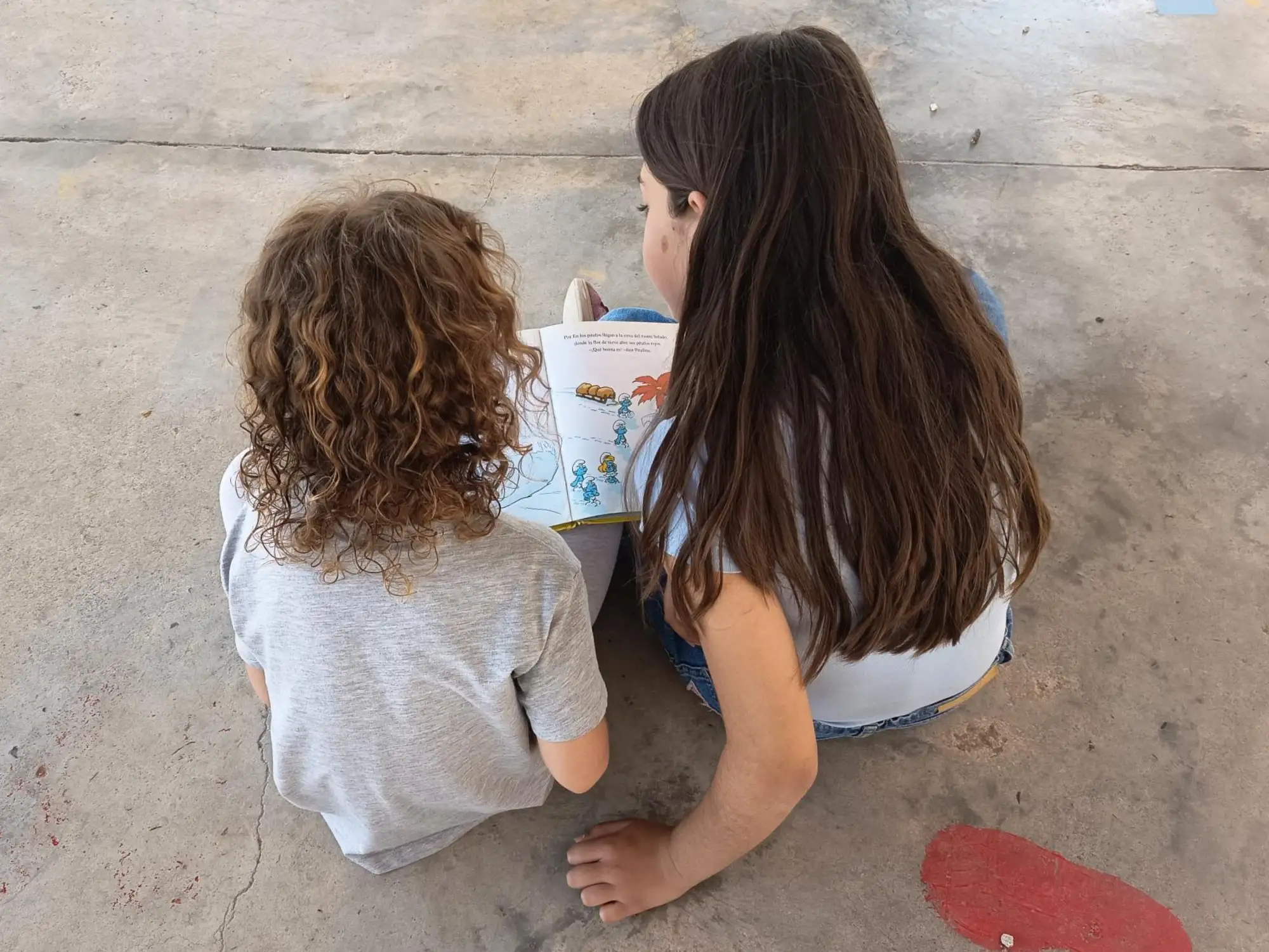 niña de primaria leyendo a niña de infantil